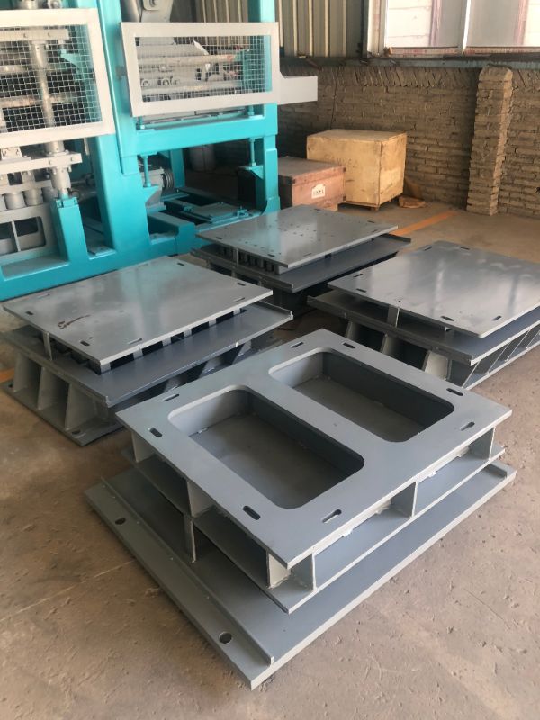 Multiple finished concrete moulds beside block making machine